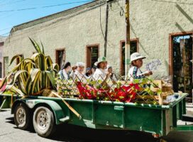 Colorful parade float with people in traditional attire and agave plants in Pachuca, Mexico.