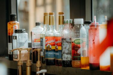 A variety of bottles including syrups and condiments on a café counter.