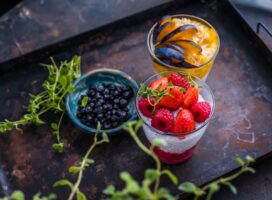 Fresh berry and fruit parfaits beautifully presented on a rustic tray.