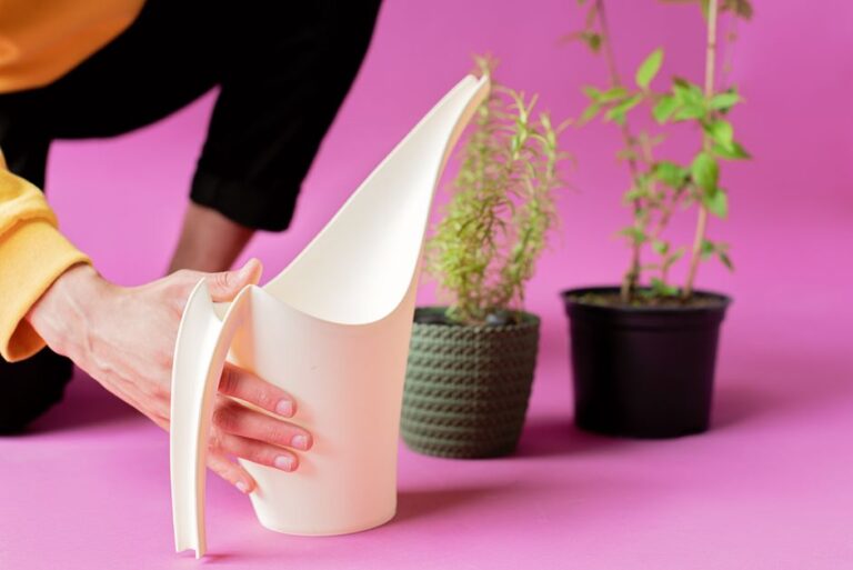 A person watering potted plants with a white watering can against a pink background.