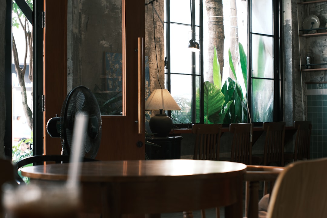 Cozy cafe interior with wooden tables and plants.