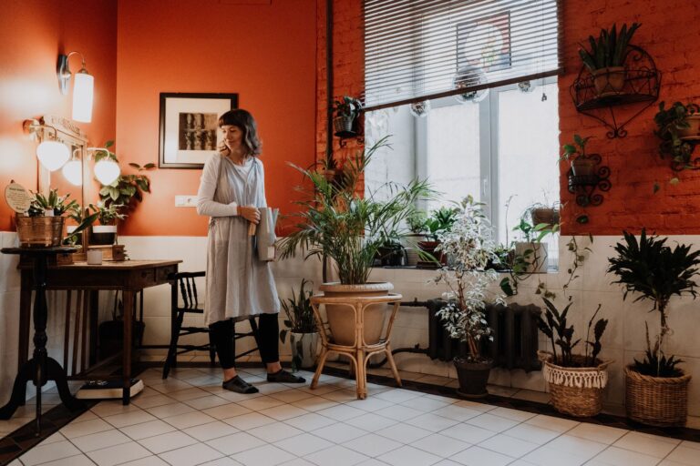Woman arranging indoor plants in a stylish, warm-toned room.