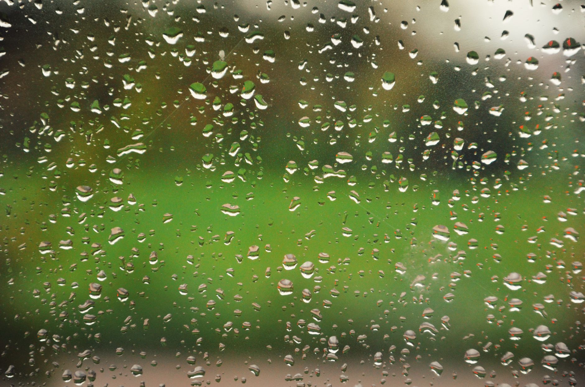 Raindrops on glass during a rainy day, creating a serene and natural pattern.